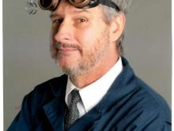 Chris Jones, picture of a person in a lab coat with safety goggles on their head in front of a plain background