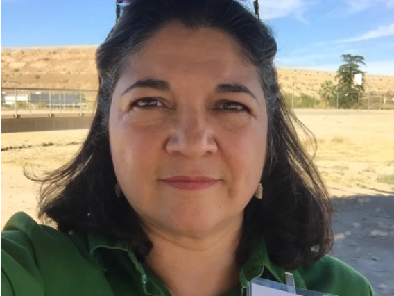 Picture of a person in a field wearing a green shirt and project harvest nametag on their lapel