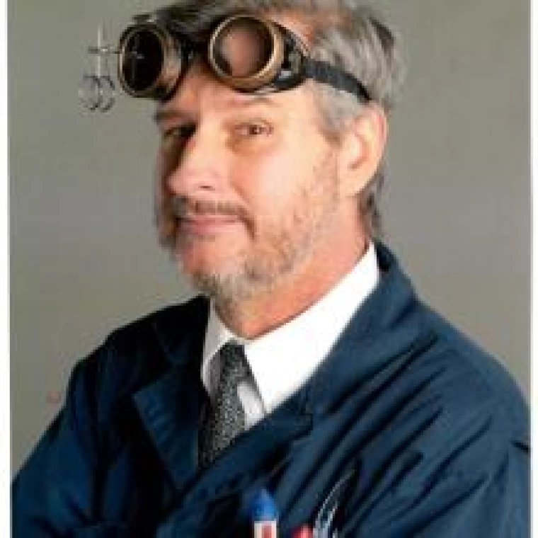 Chris Jones, picture of a person in a lab coat with safety goggles on their head in front of a plain background