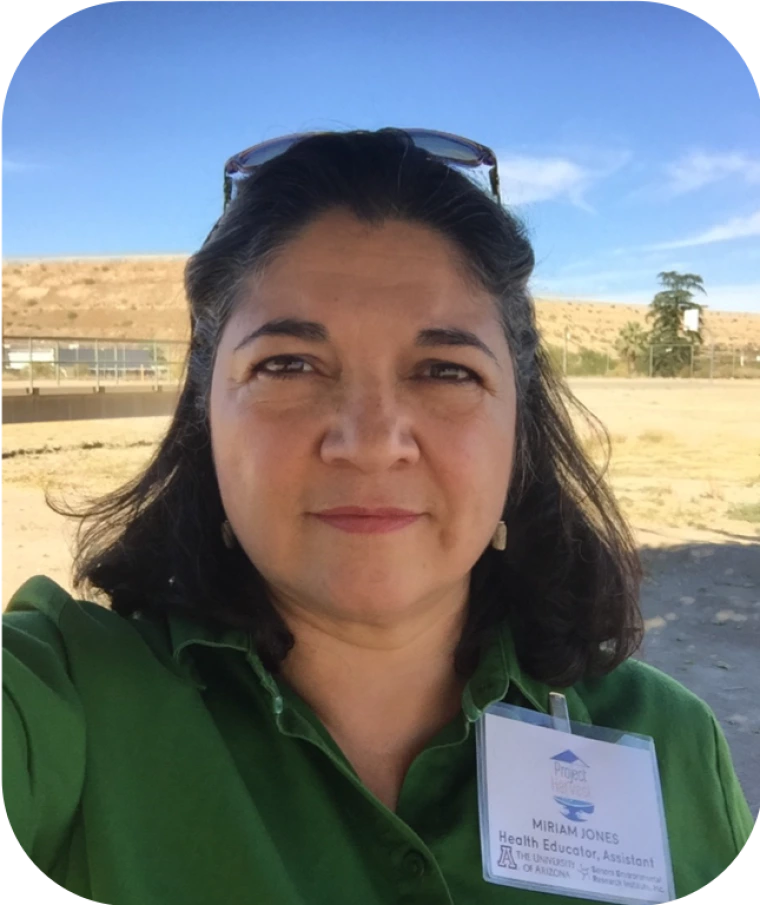 Picture of a person in a field wearing a green shirt and project harvest nametag on their lapel